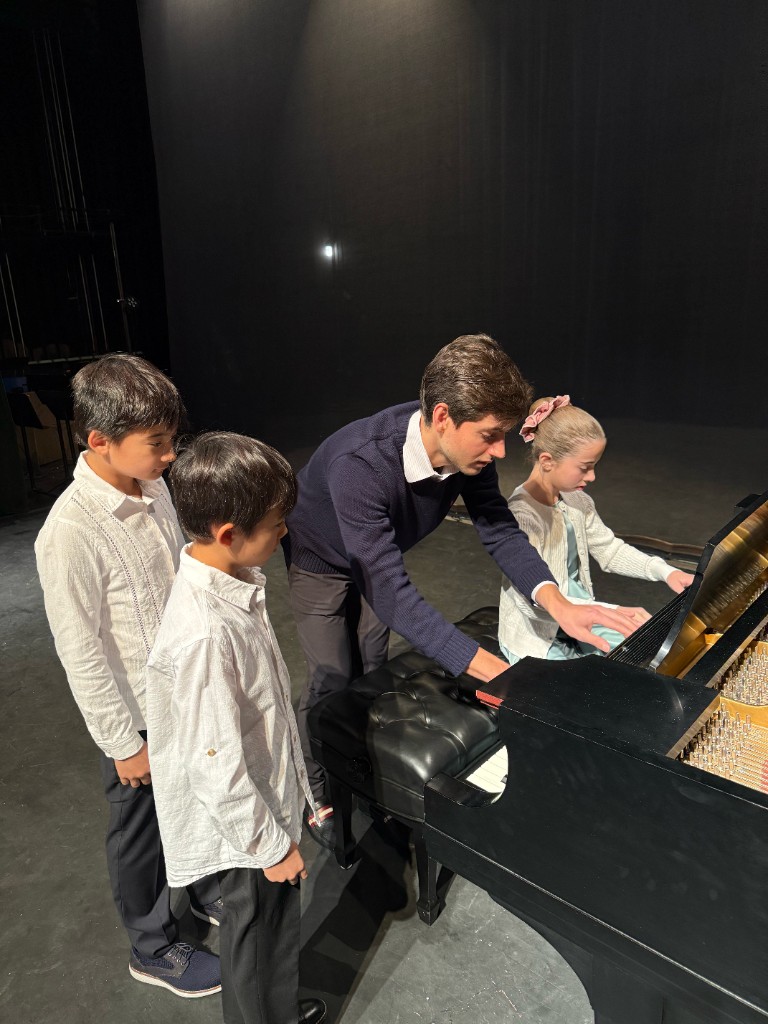 Artem Alexanian guiding a student at the piano while others observe