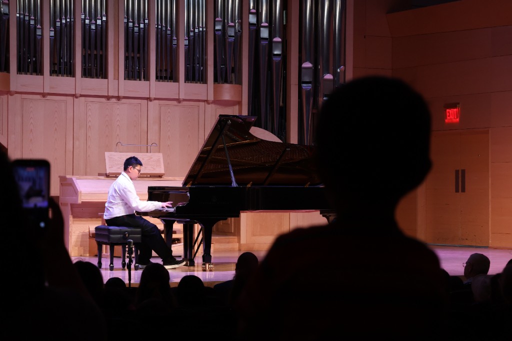 Student performing on stage at a recital with audience